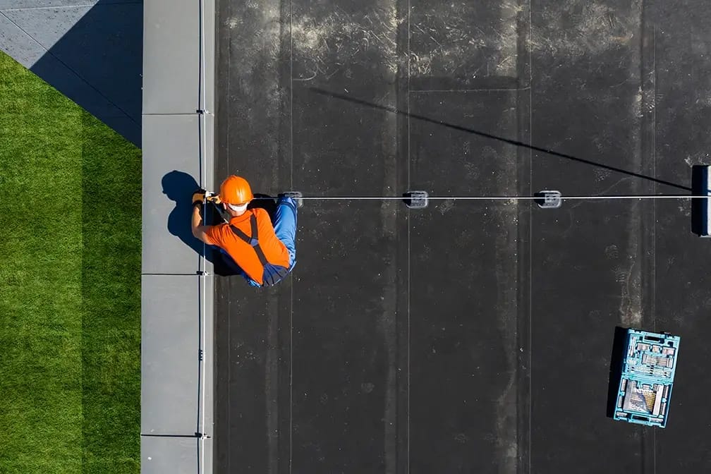 Top-down view of Roofing contractor in hardhat on roof