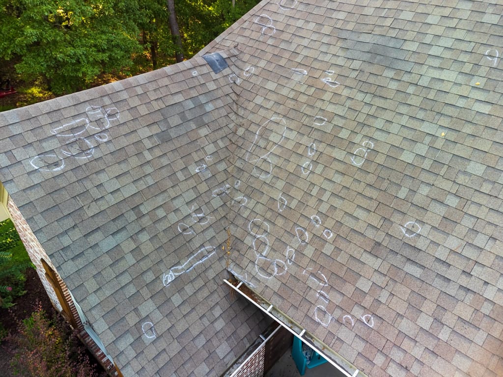 large house roof with hailstorm damage marks on