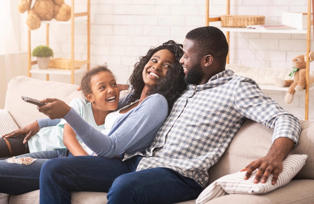 parents and their daughter watching tv on couch