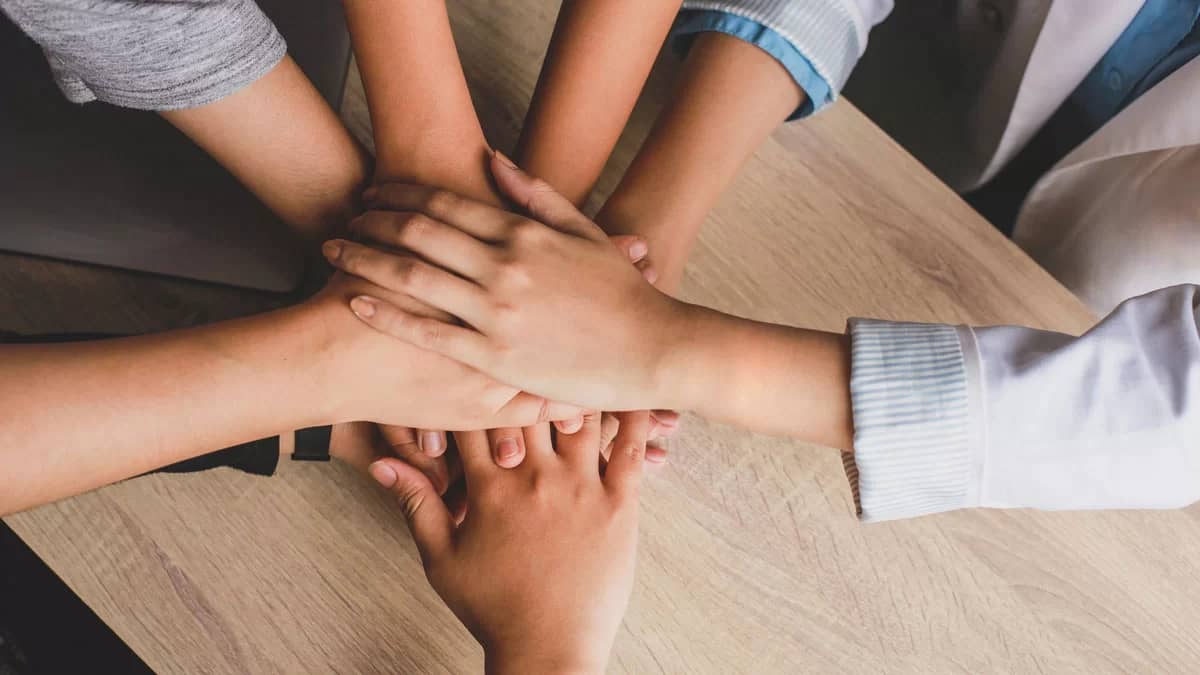 A group of roofing teammates with their hands in the center of a circle