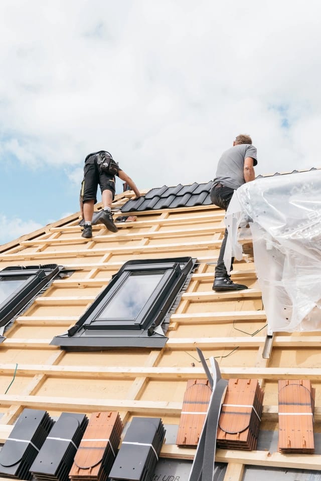 roofing crew building a new roof on house
