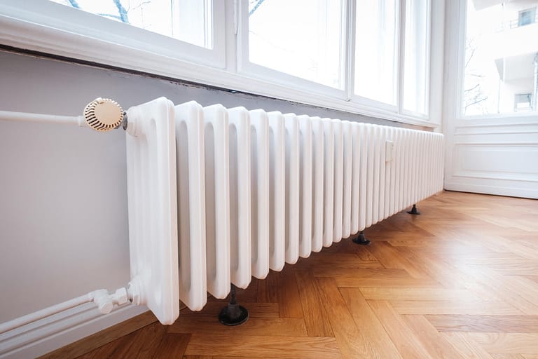 radiator heater-white radiator on wood flooring beneath a window