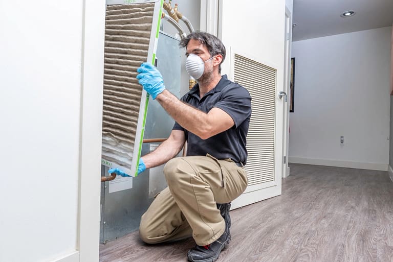 a man wearing a mask and gloves holding a air filter