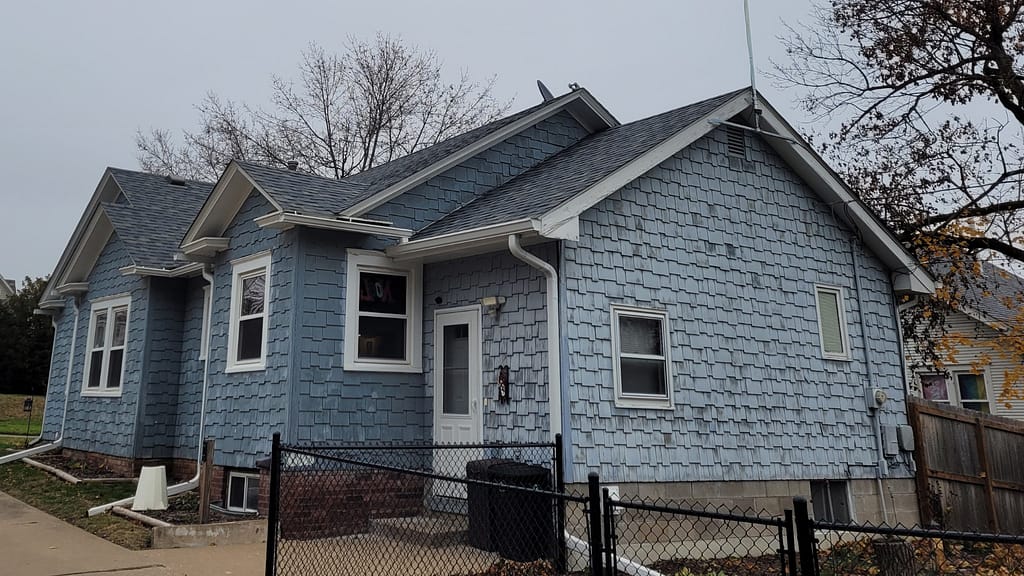 An Oskaloosa, Iowa home with blue siding before a full siding replacement.