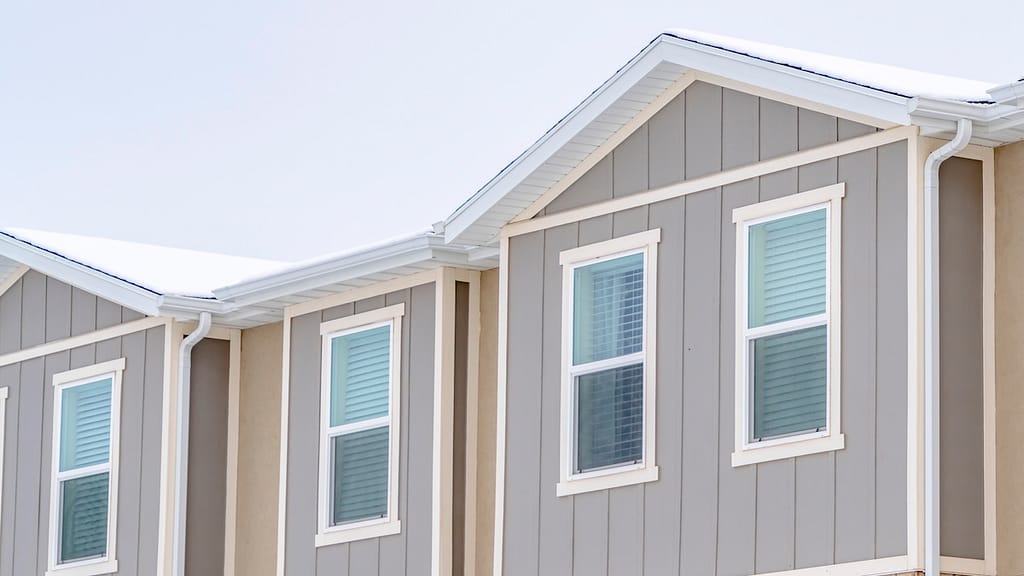 A close-up architectural view of multi-unit residential gables featuring neutral-toned vertical board and batten siding, showcasing the durable finish that influences the overall Hardie board siding cost and long-term value.