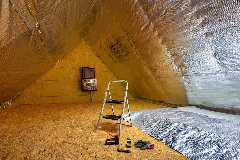Laying the thermal insulation foil on the insulated attic in the house