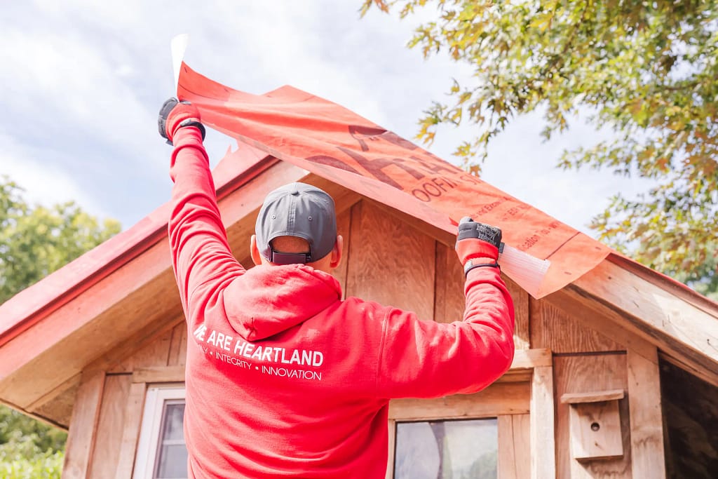 roofing companies in hopkins worker installing plastic on top of roof
