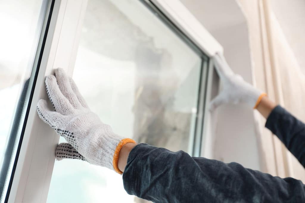 handyman with white gloves installing windows