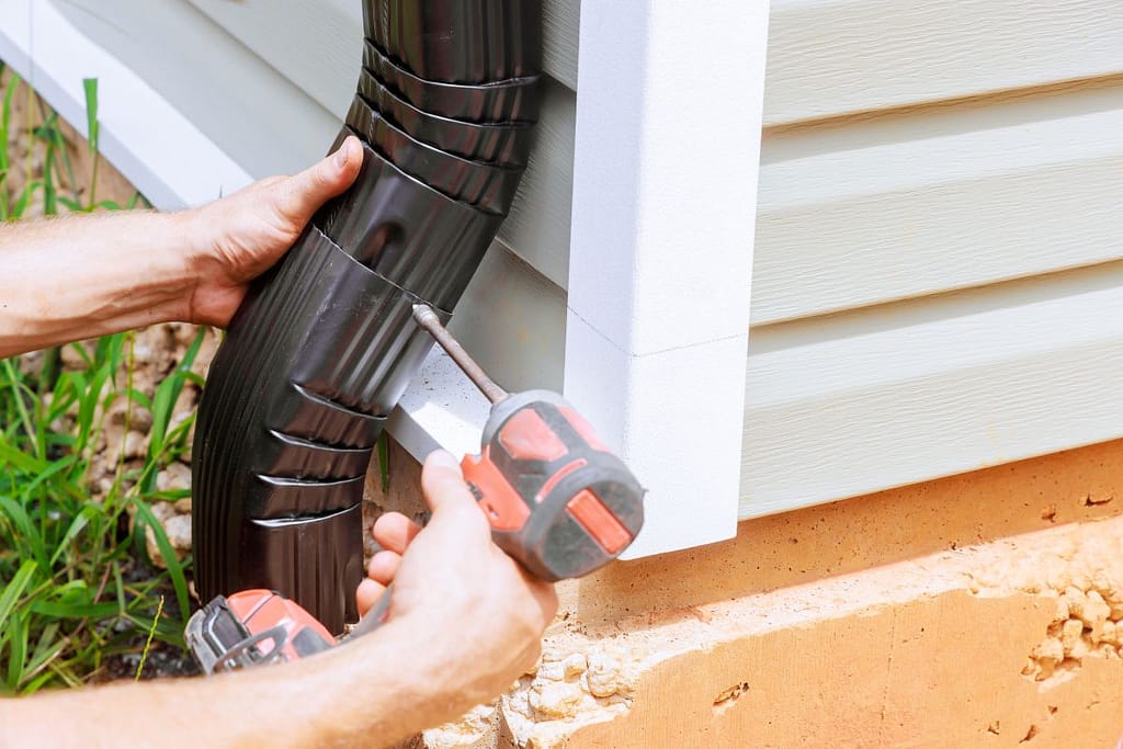 Installing rain gutter on roof with an professional is fitting downpipe, downspout bend running