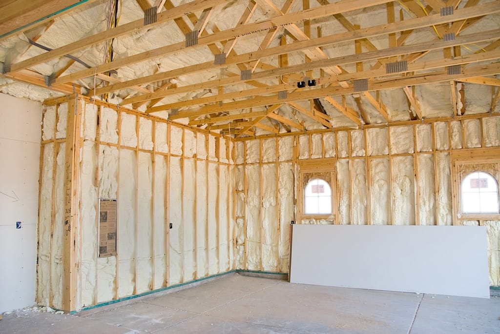 A room at a newly constructed home is sprayed with liquid insulating foam before the drywall is added. Ideal for new home construction advertising and other home construction promotional inferences.