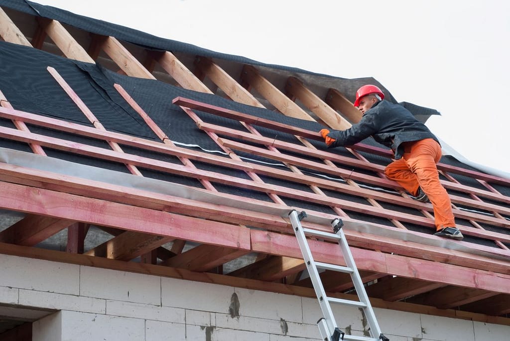 commercial roof replacement worker replacing shingles wooden board