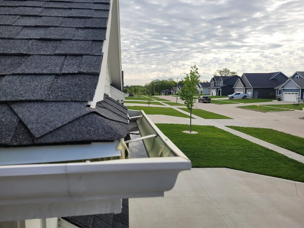 seamless gutter installation close up blue shingles roof