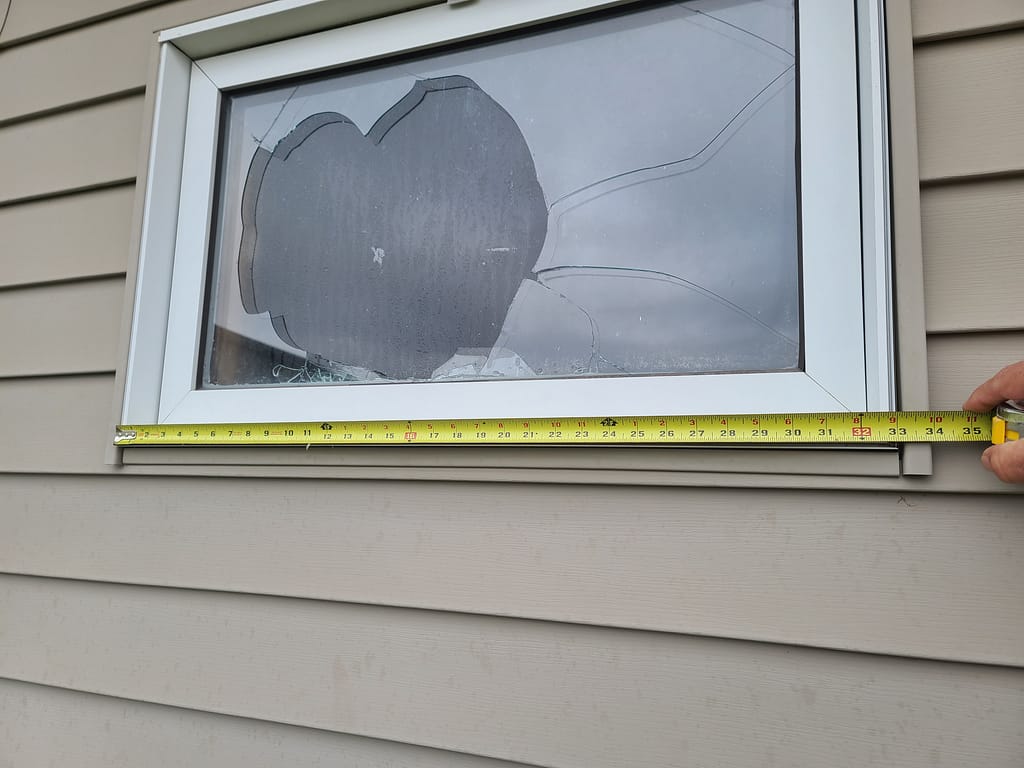 Hail-damaged window with broken glass at an Iowa home.