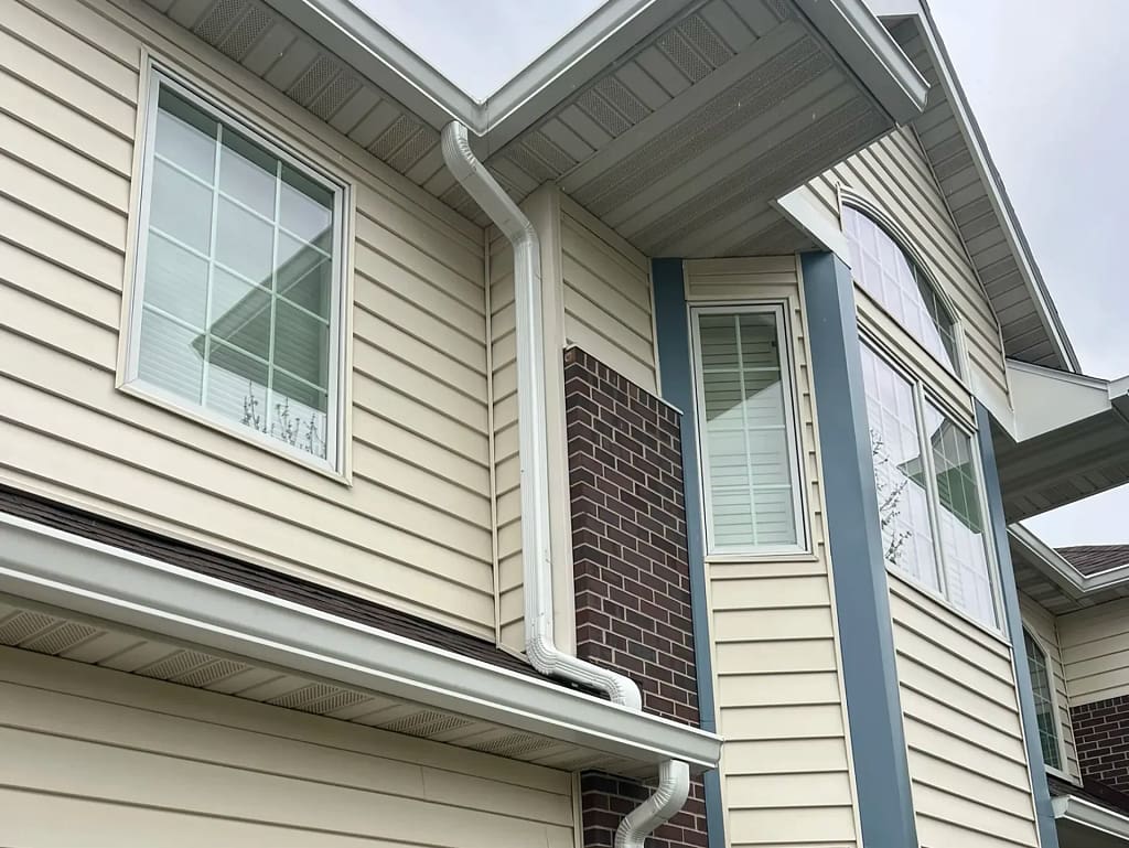 seamless gutter installation yellow siding big house