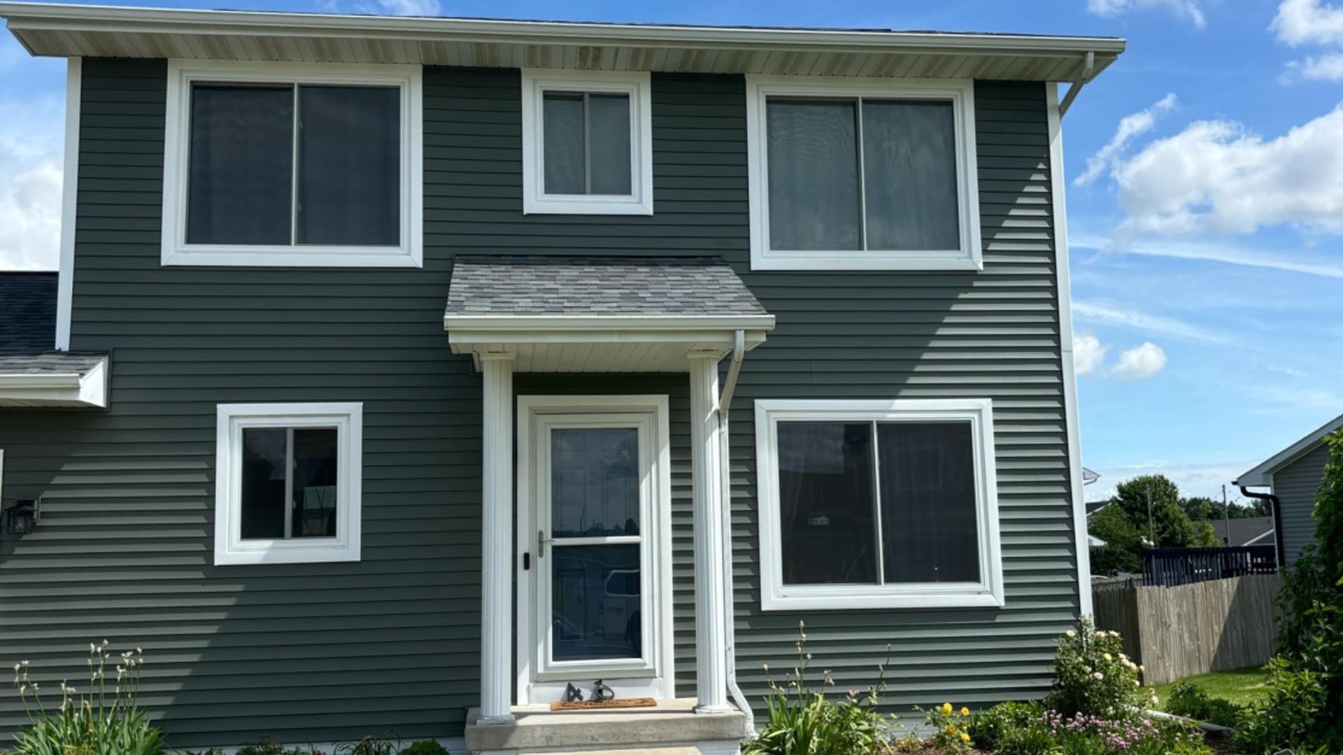 A two-story house in Ames, Iowa with Alside Odyssey Plus siding in Deep Moss, new gutters, and wraps.