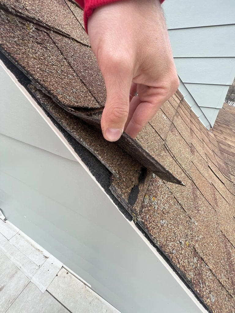 Heartland inspector checking shingles during a roof inspection in Iowa.