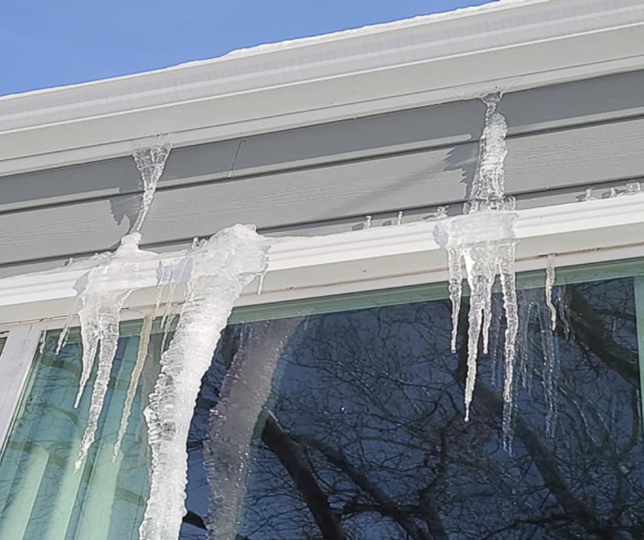 Ice dams forming along the edge of a house roof in Iowa during winter.