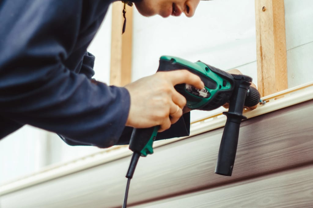 man installing new siding on house