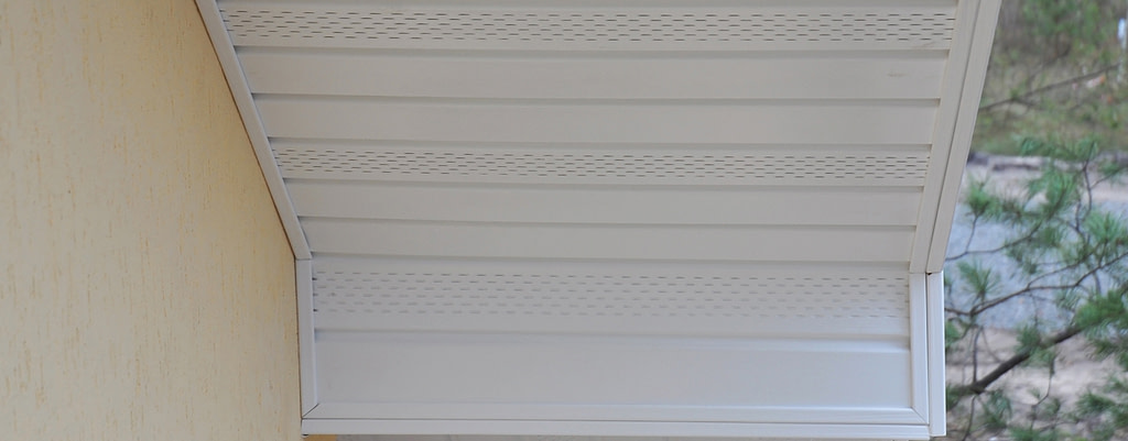 Close-up of white perforated soffit vents along a roof overhang corner