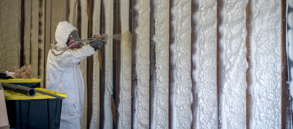 Person spraying insulation on wall