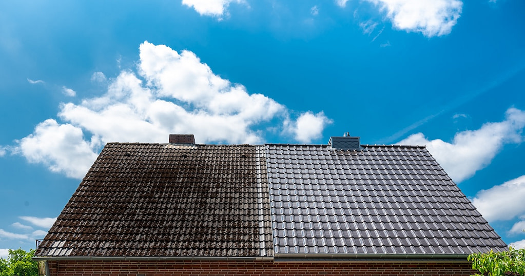 A half cleaned house roof shows the before and after effect of a roof cleaning.