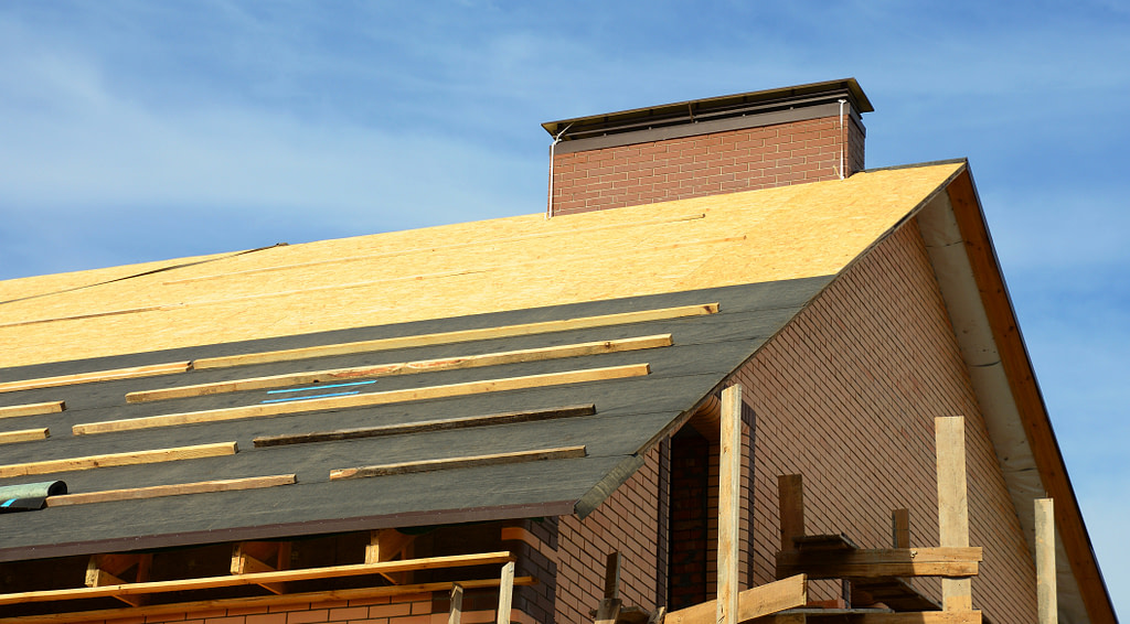 roof underlayment types Roofing construction on the stage of roofing underlayment installation on the roof deck, roof sheathing.