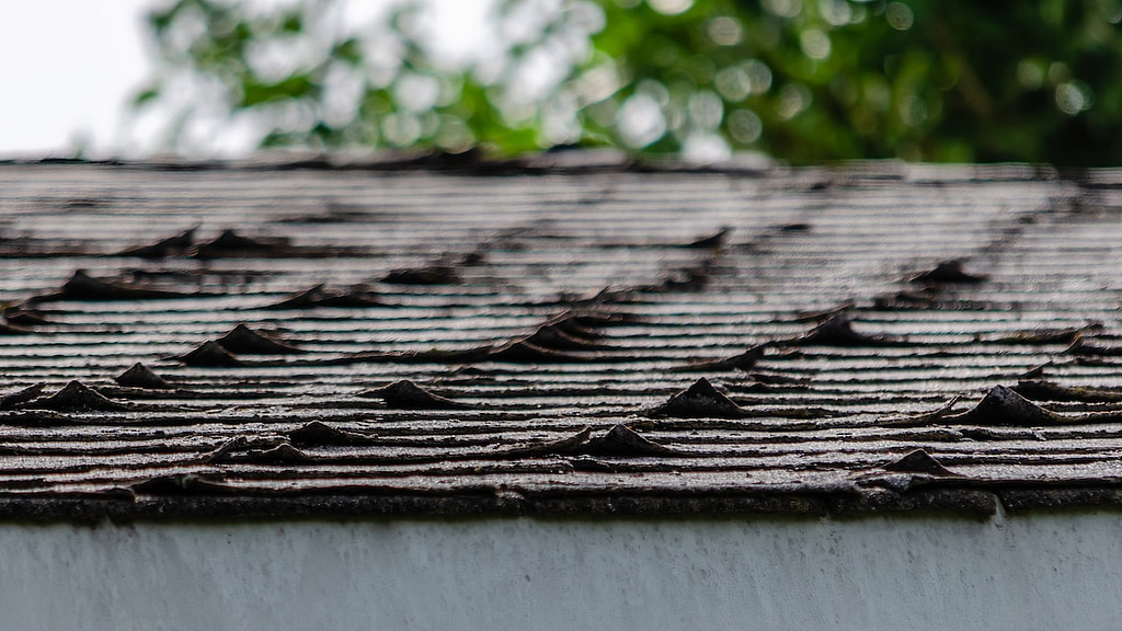 Close-up of curled roofing shingles on a residential rooftop