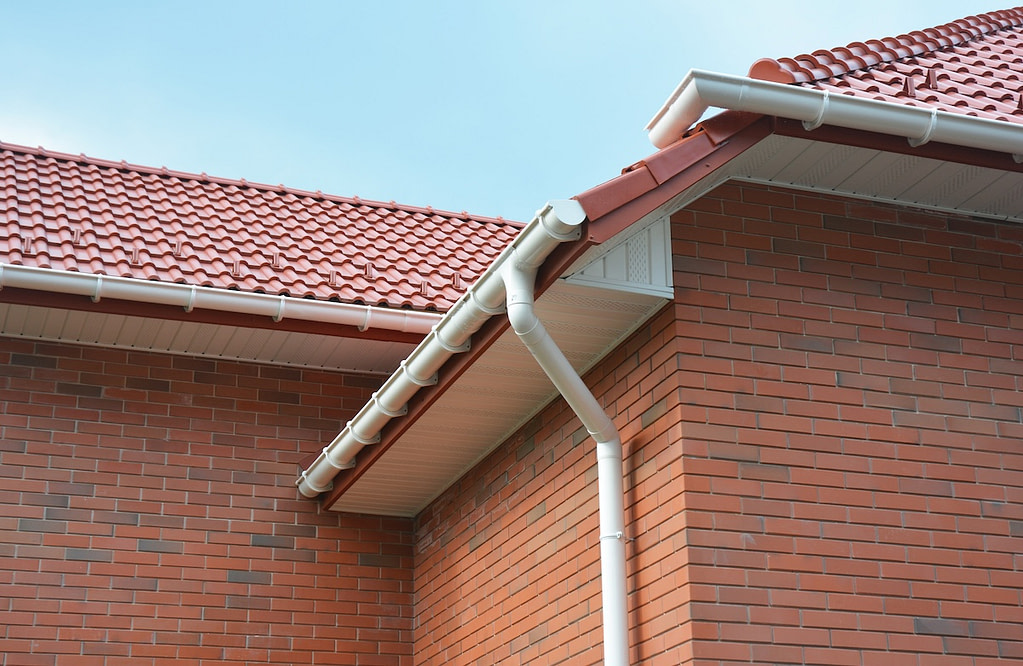 A close-up on plastic rain gutters, downspout, soffit and fascia