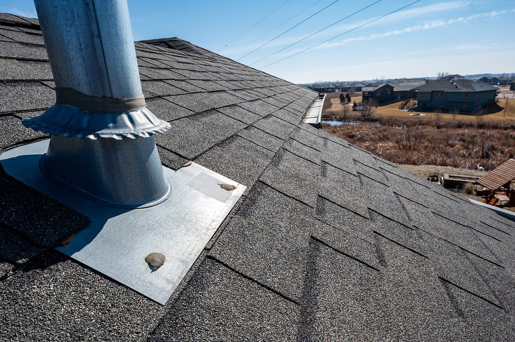 Vent on a shingle roof with silicon caulking and flashing for a water tight seal