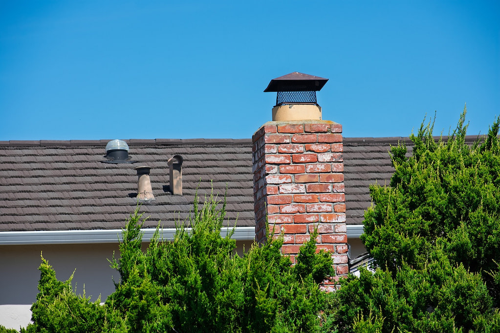 Red brick chimney with a black cap