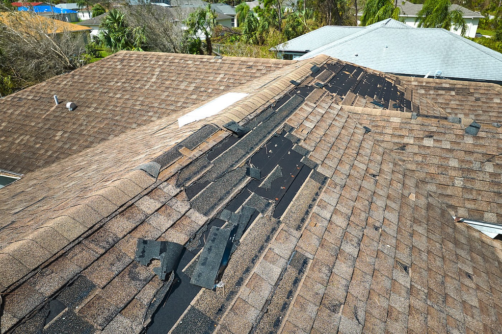 Damaged house roof with missing shingles