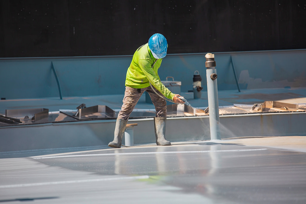 worker holding an industrial spray gun used for roof plate tank surface on steel industrial painting