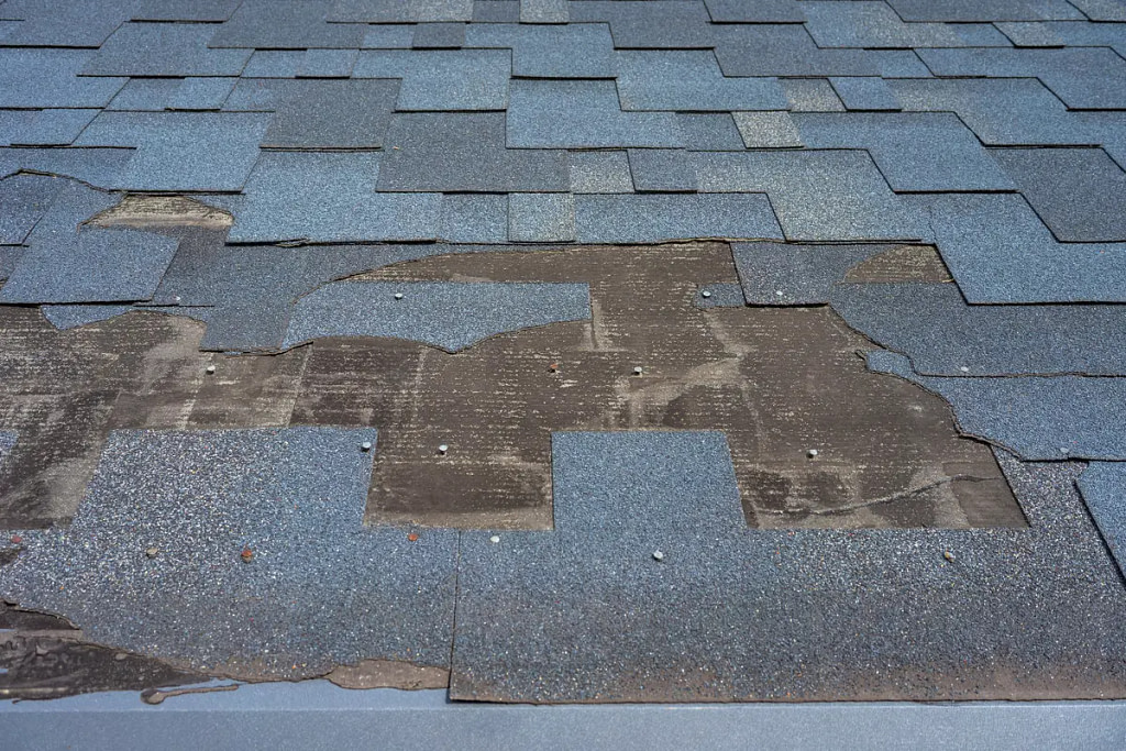 Roof that is in need of asphalt roof repair. Missing and peeling shingles.