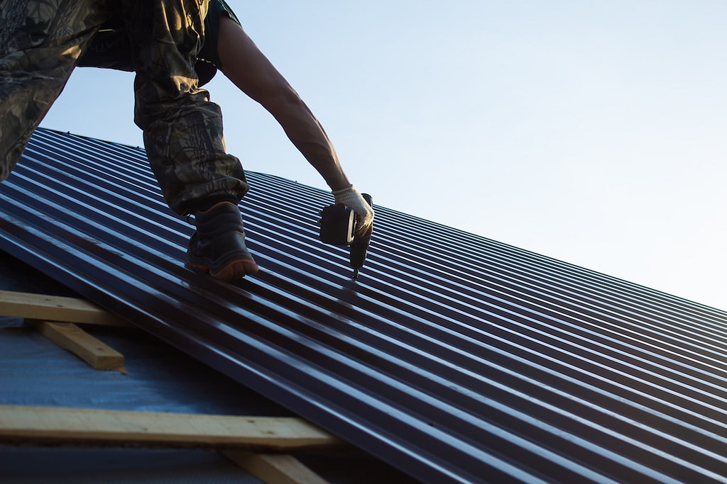 Worker screwing down metal roofing material