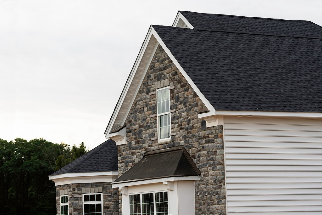 Black roof shingles on white house with stone accents