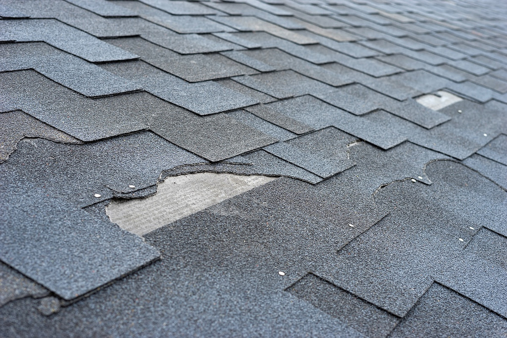 Сlose up view of asphalt shingles roof damage that needs repair.