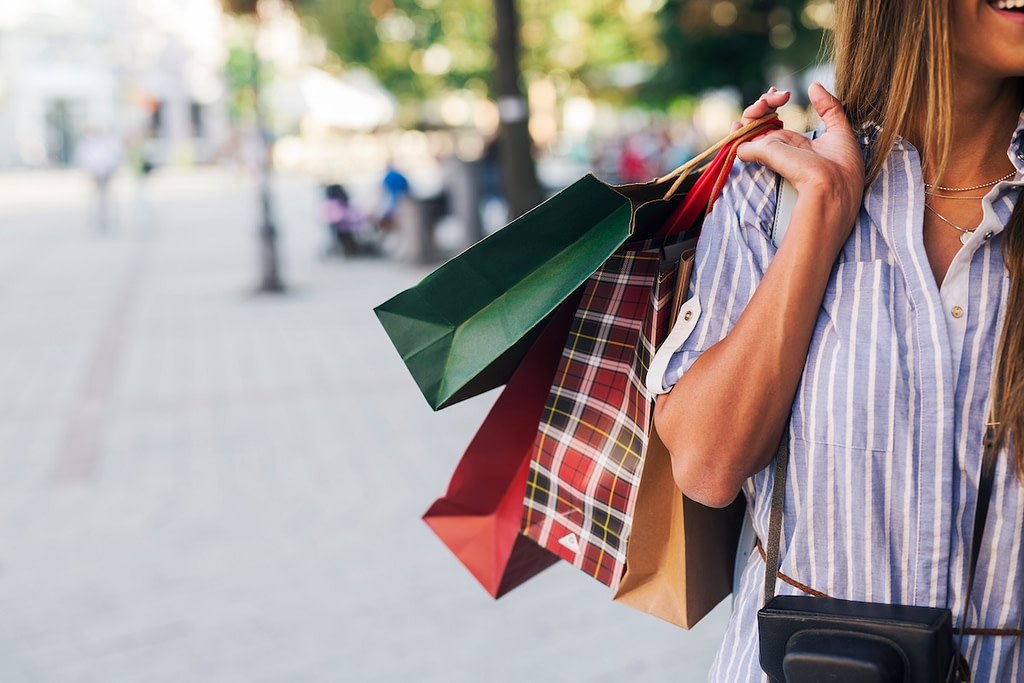 Pretty tourist woman holding shopping bags in city