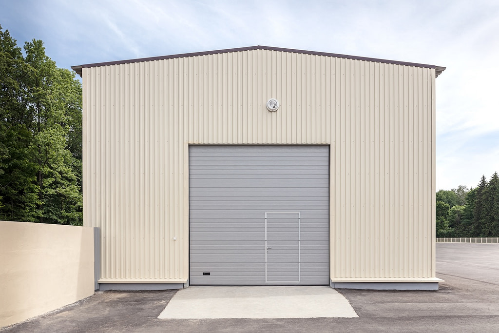 facade of industrial storehouse with closed gray metal gate and door