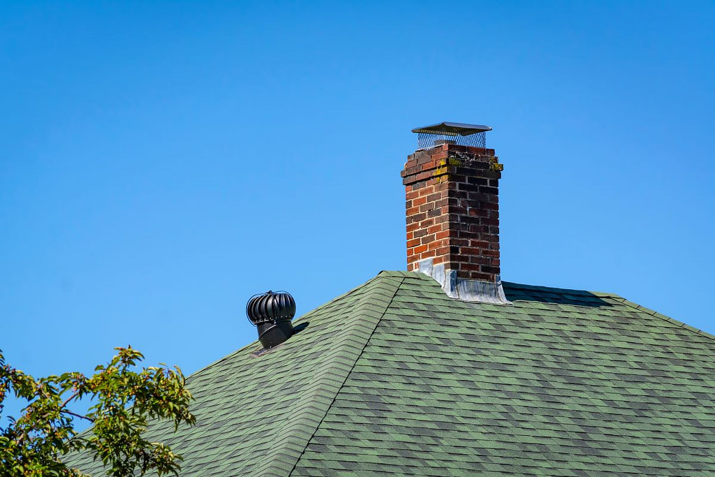 brick chimney with chimney cap against blue sky