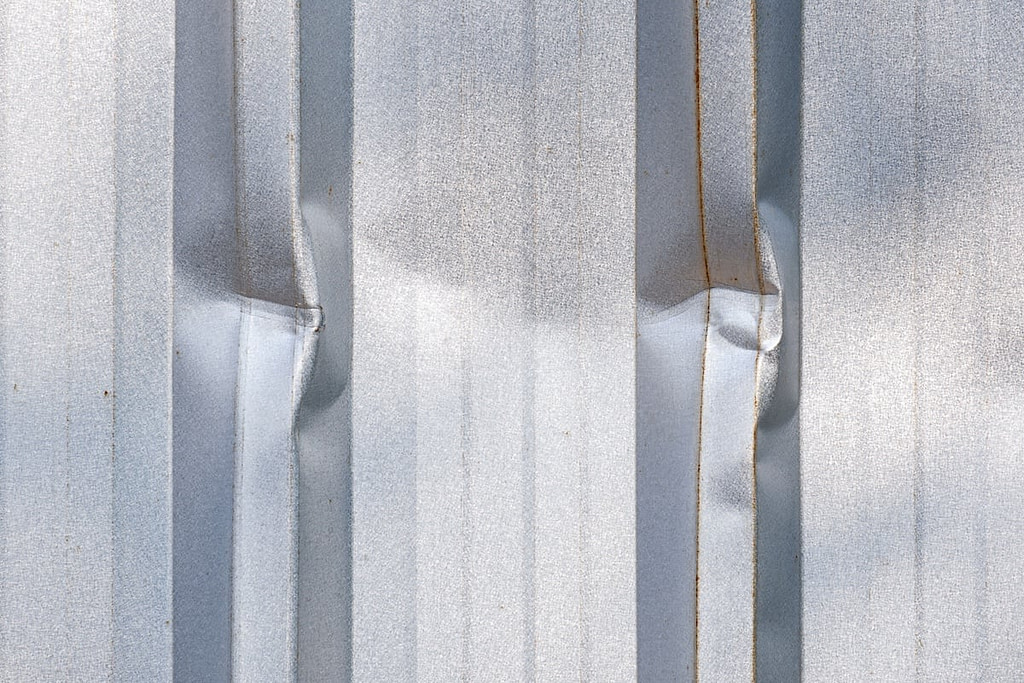 Close up dents on surface of corrugated metal wall