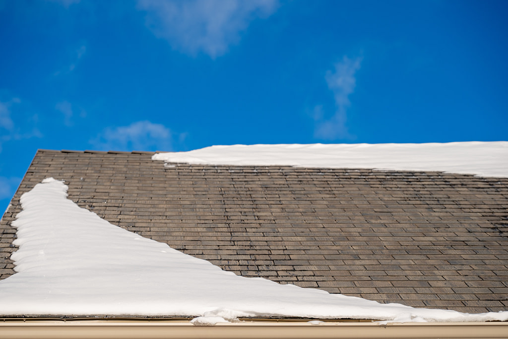 Snow and ice along a residential roof gutter forming a dam in the winter.