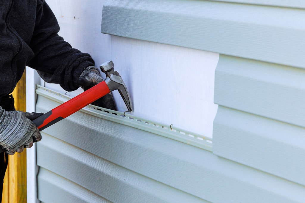 As part of an exterior house renovation, damaged plastic siding is being a replaced