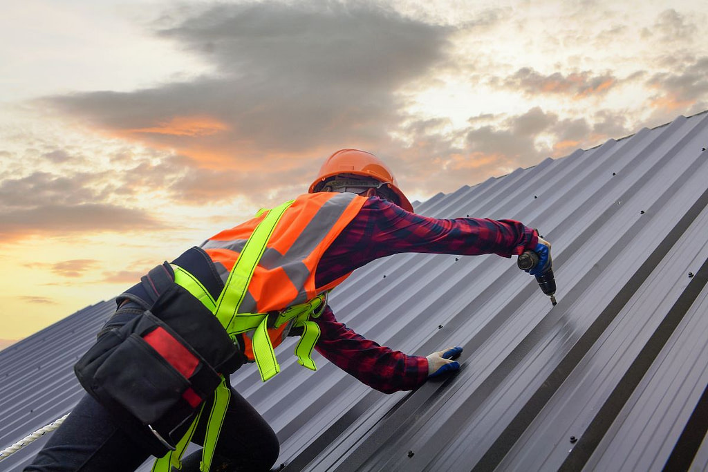 construction worker repairing metal roof