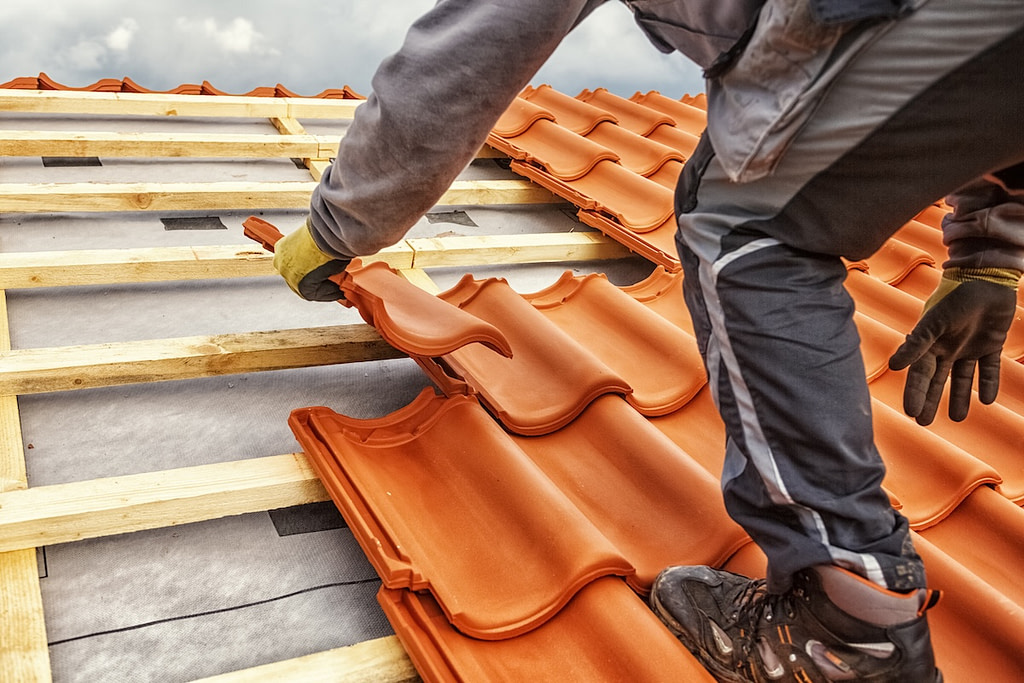 Roofer at work, installing clay roof tiles
