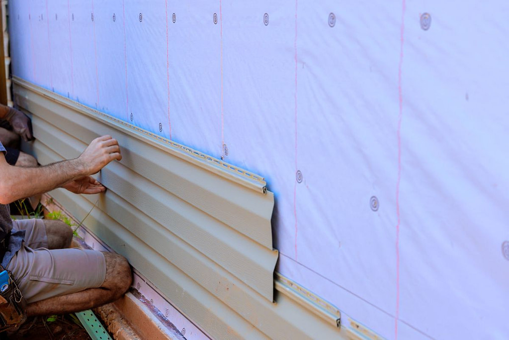 During construction of new home, handyman installs vinyl PVC siding