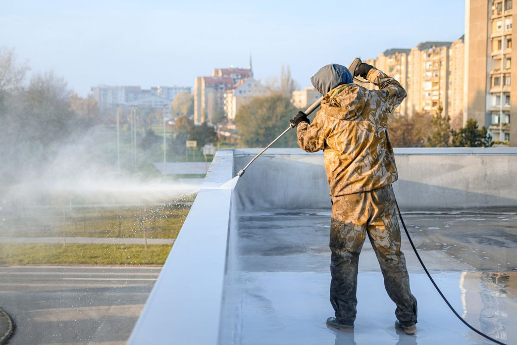 commercial roofing services worker cleaning roof edge