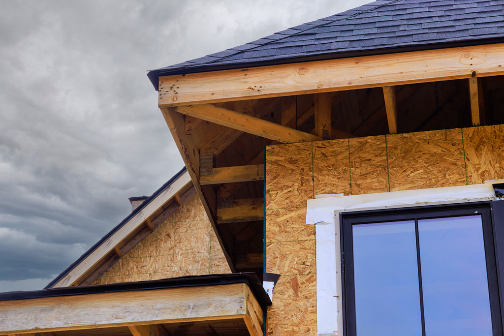 how to replace fascia board An under construction house has its joist framework with plywood installed, gutter holders, soffit fascia trim installed