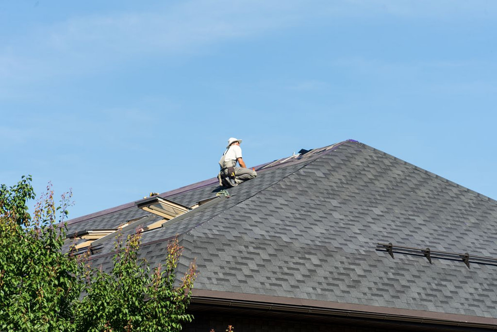 roof replacement cost Albert Lea MN worker on top of shingles roof
