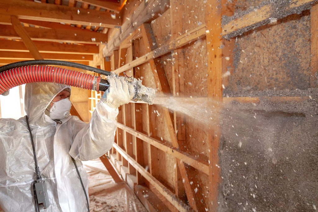 Spraying cellulose insulation on the wall