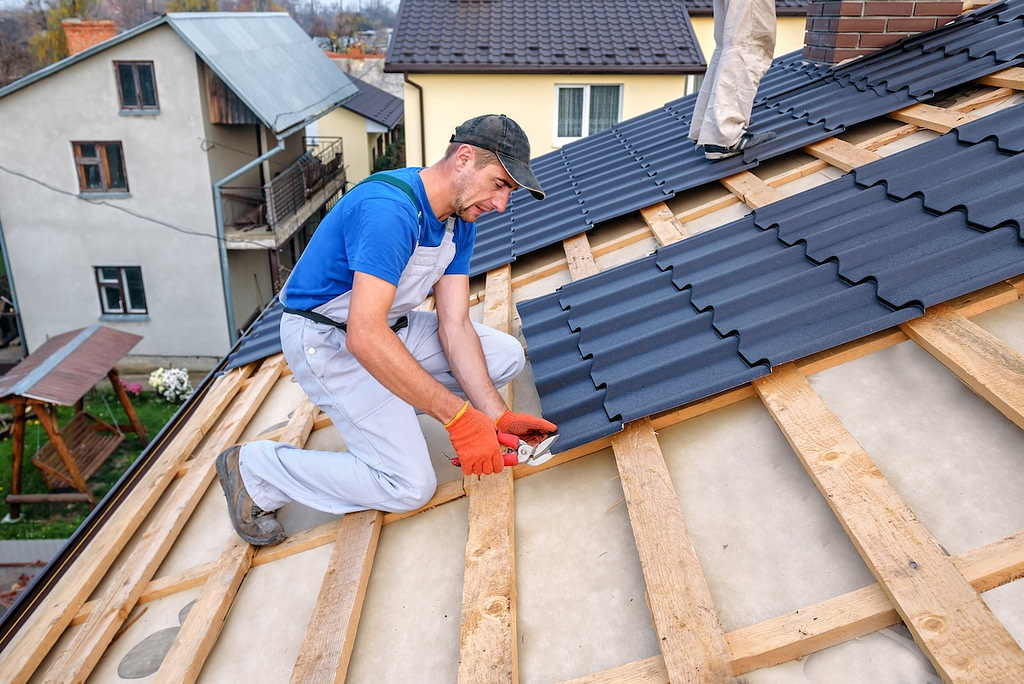 a professional roofer installing black metal roofing